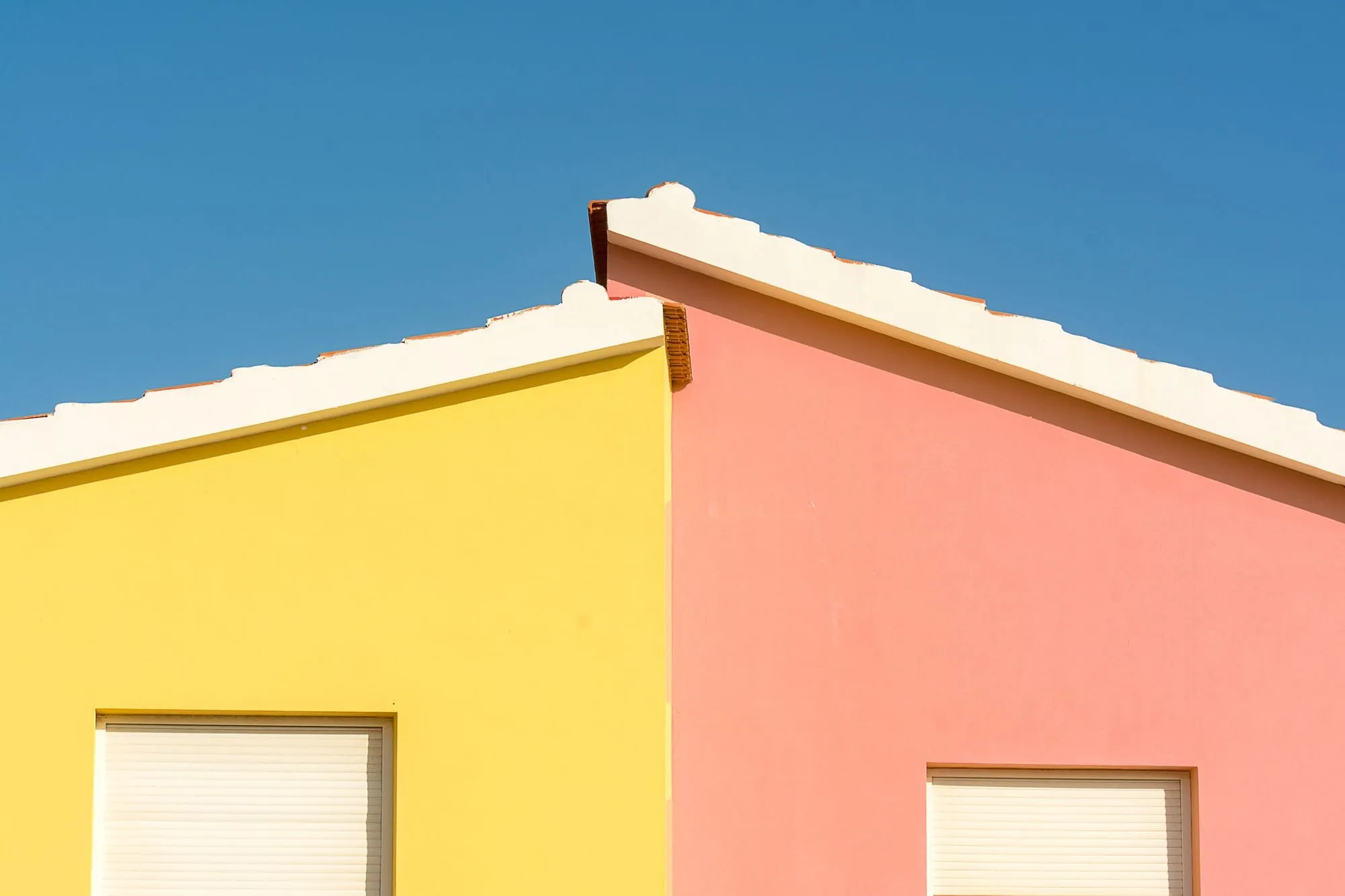 Gelbe und rosa Hausfassade vor blauem Himmel